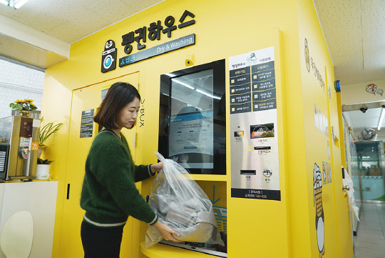 한 소비자가 서울 산천동에 위치한 세븐일레븐 점포에서 무인 세탁 시스템을 이용하고 있다.  세븐일레븐 제공